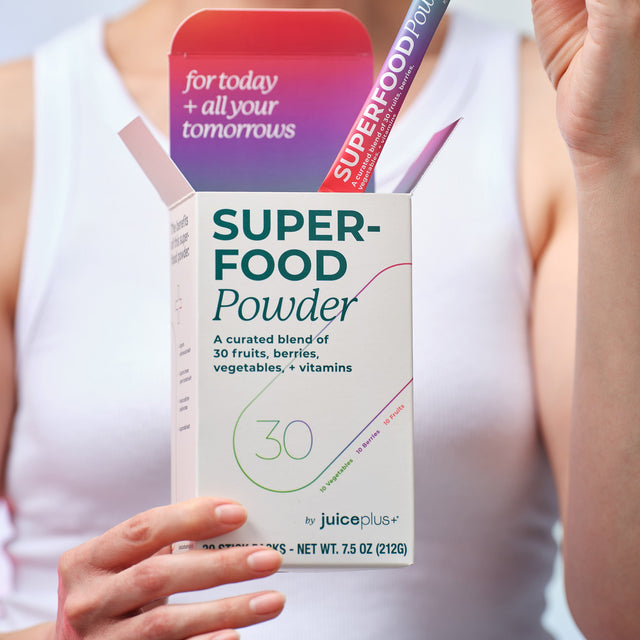 Box of Juice Plus+ Superfood Powder held by a person